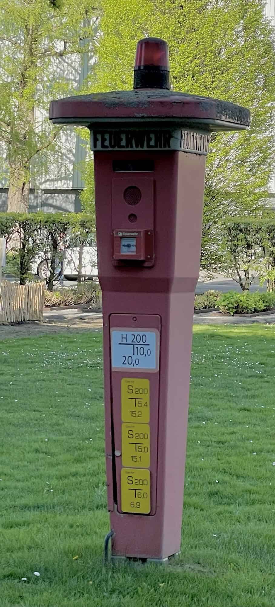 Eine alte rote Feuerwehrrufsäule auf dem Rasen des Messegeländes.