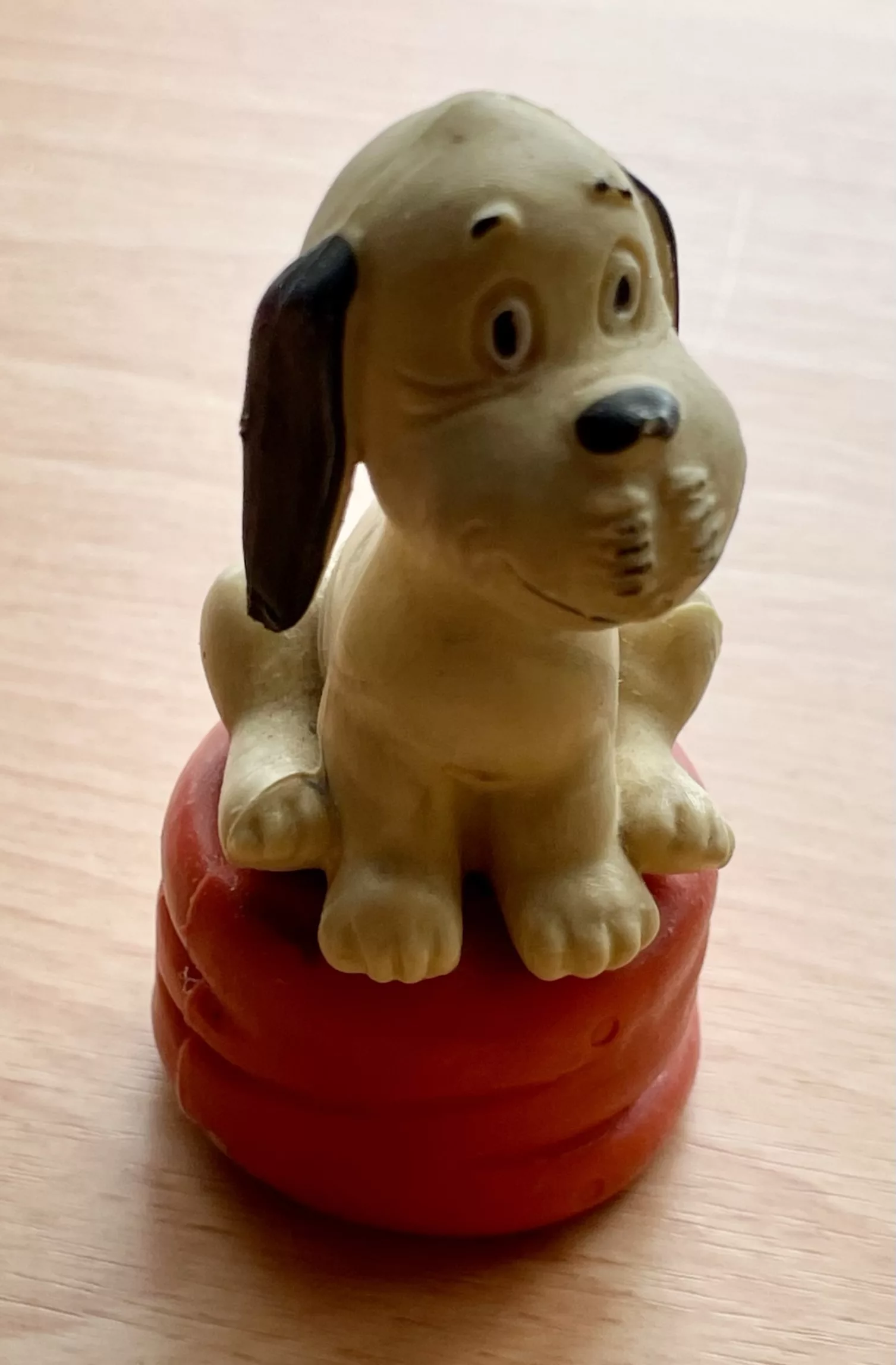 Plastikfigur Hund Wum von Loriot auf rotem Sitzhocker.
