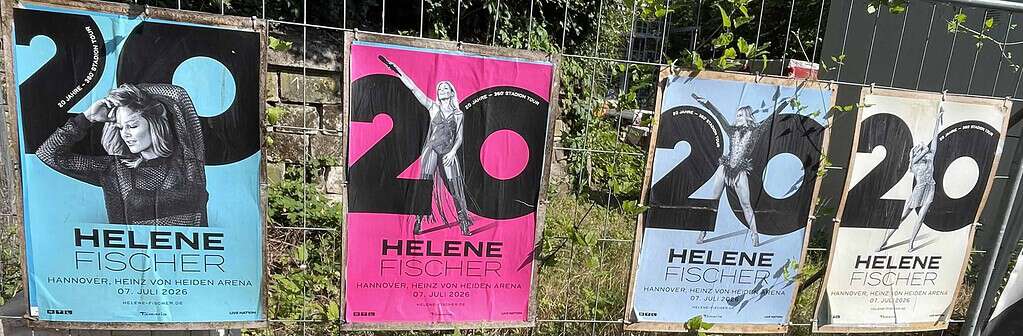 Vier unterschiedlich farbige Konzertplakate von Hele Fischer am Bauzaun.