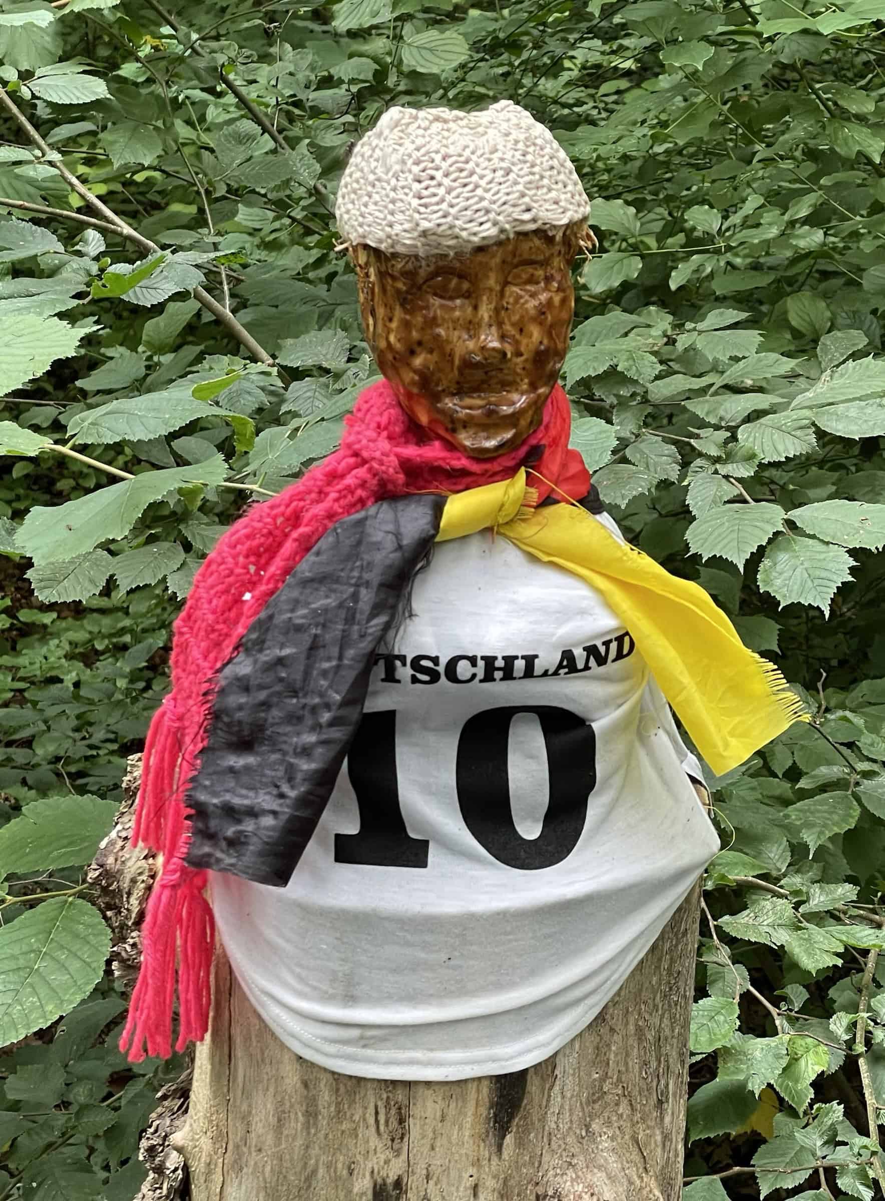 Holzfigur auf Holzstamm im Deutschen Fußball-Fanoutfit..