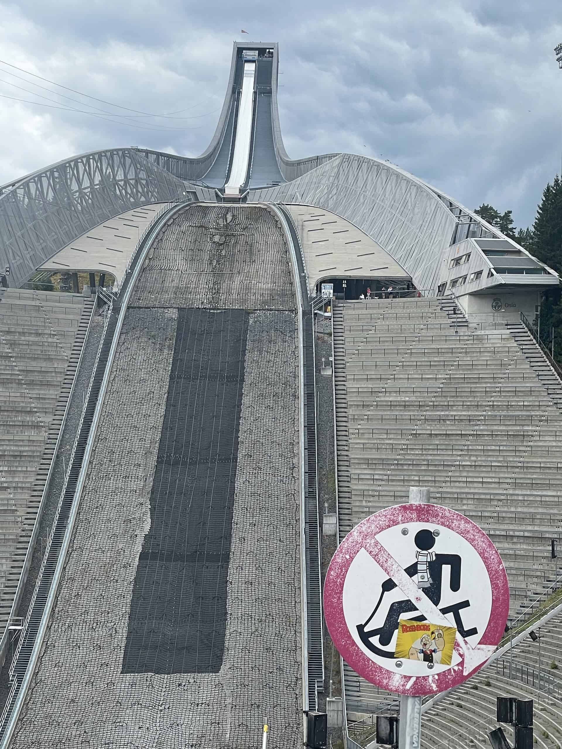Skispringschanze Holmskollen im Sommer und Rodeln-verboten-Schild im Vordergrund.