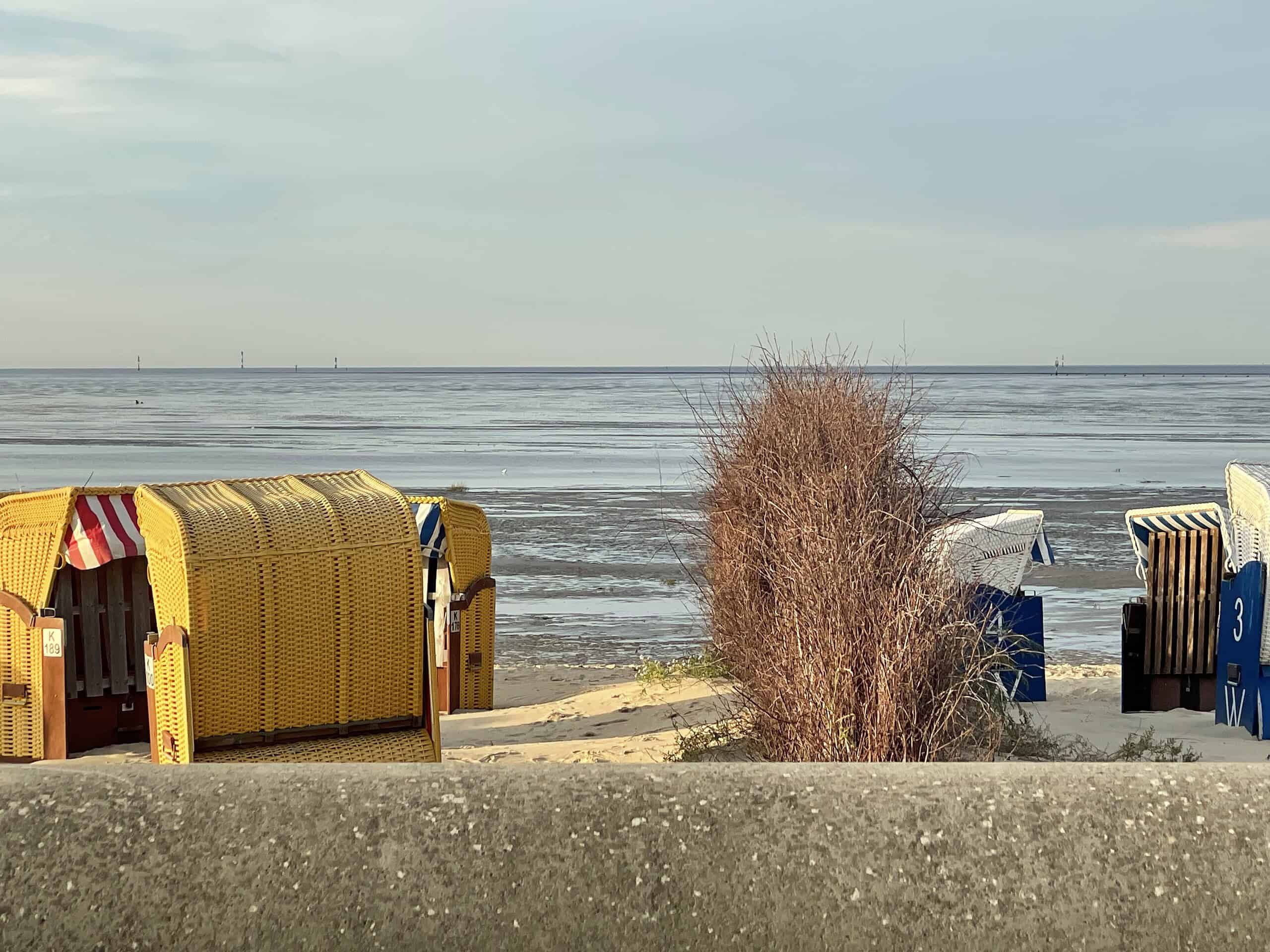 Über die Betonmsuer geschaut: Libks gelbe, rechte blaue Strandkörbe, im Hintergrund dir Nordsee.
