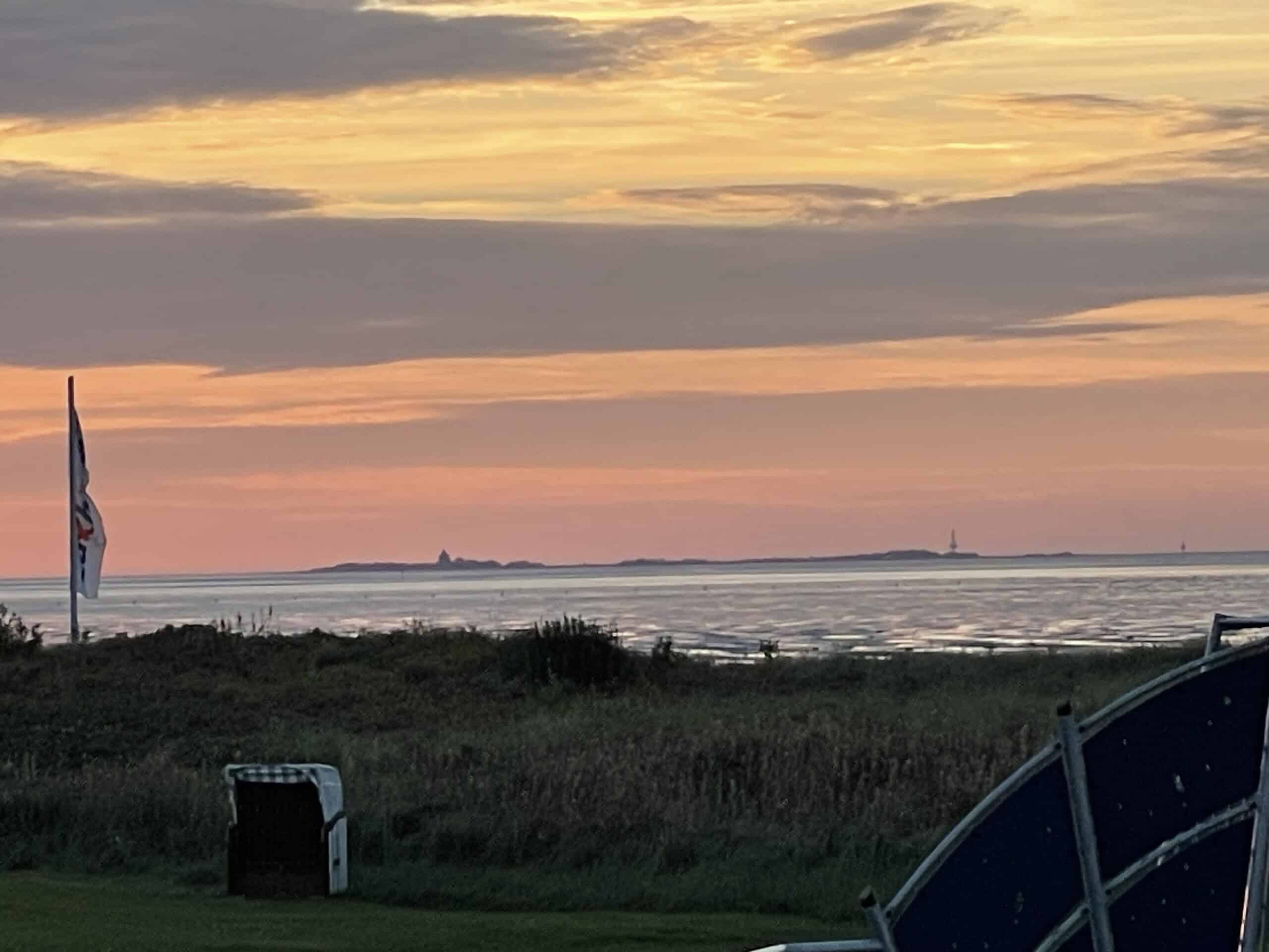 Übrr den Deich, die Nordsee und im
Hintergrund ist Neuwerk mit einem Glen-orangenem Himmel