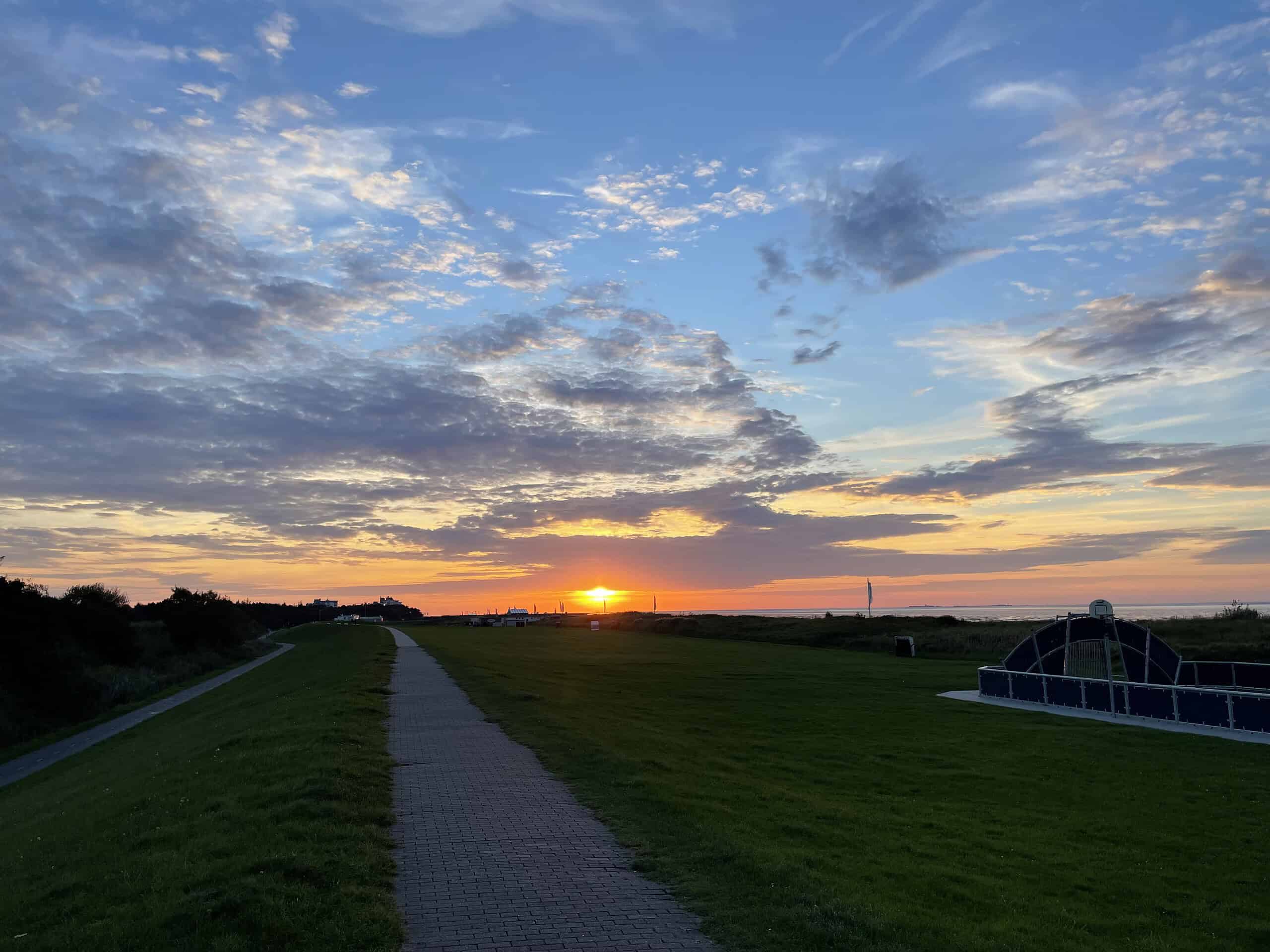 Abends auf dem Deich mit dem farbintensiven Himmel und untergehender gelber Sonne.