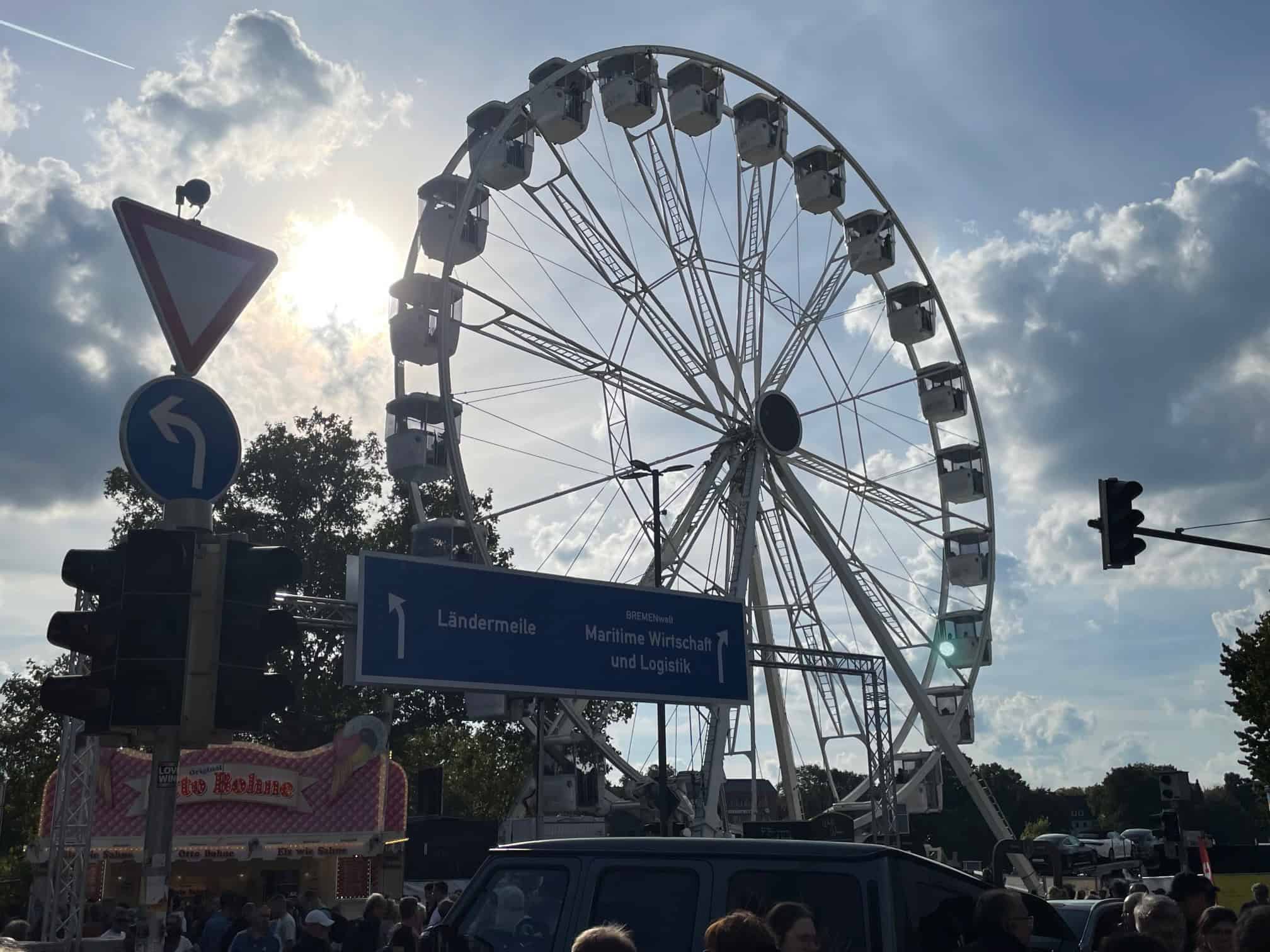 Auf der Straße mit vielen Menschen und Riesenrad im Hintergrund.
