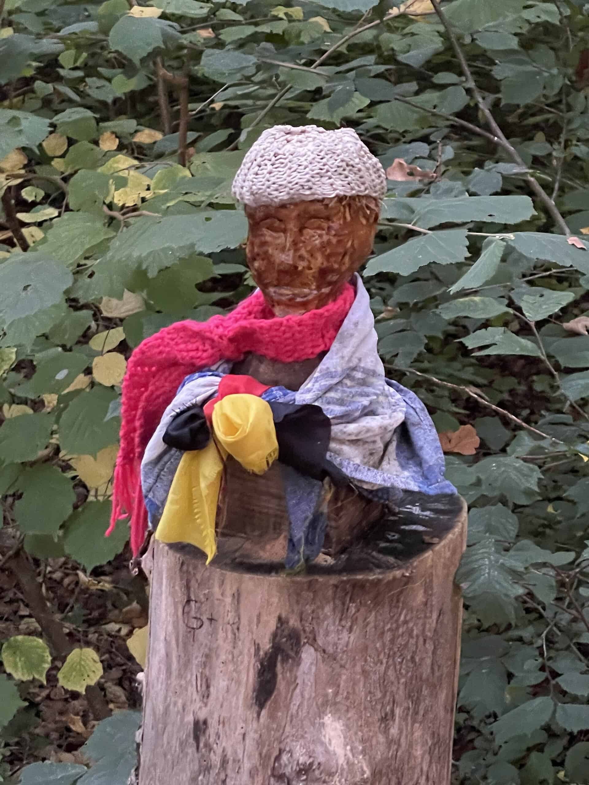 Angezogenes Püppchen auf Baumstamm im Wald.