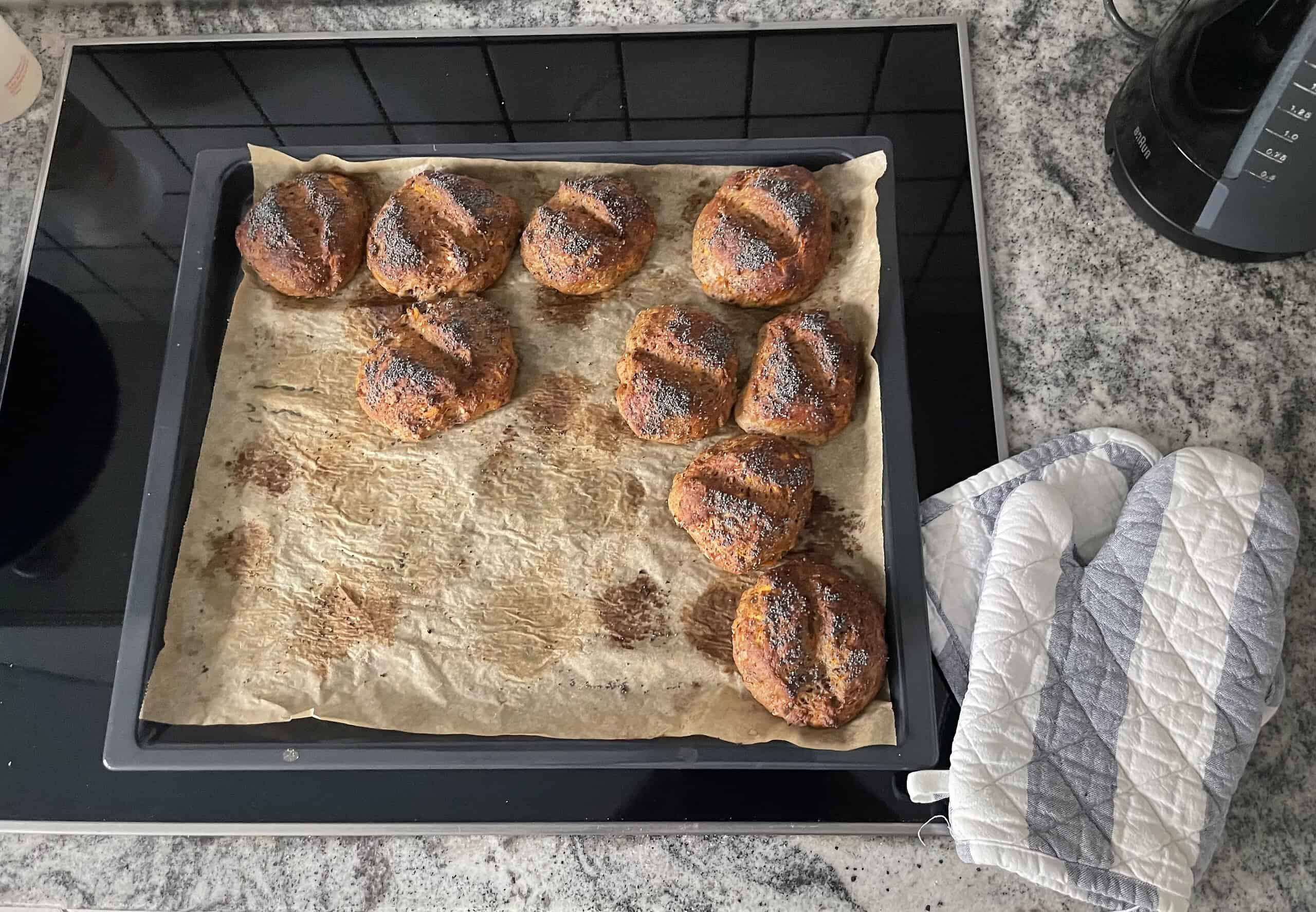 Blech mit frisch gebackenen Brötchen auf dem Herd.