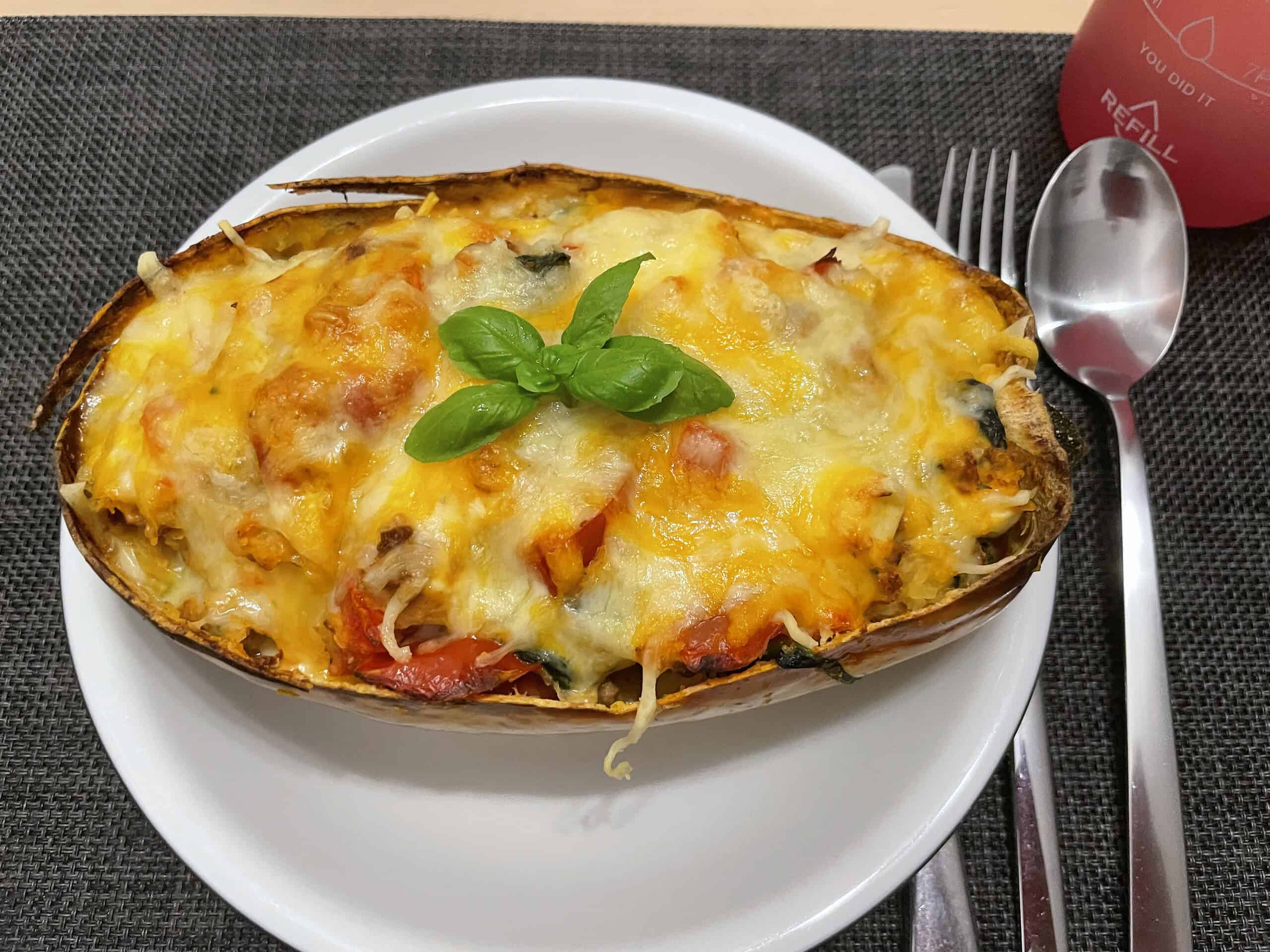 Käseüberbackenes Veganhack mit Kürbis, in halben Kürbis serviert.